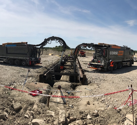 Camion aspirateur : excavation par succion sur chantier. Deux camions aspirateurs CORSE ASPI effectuent une excavation par aspiration pour dégager des canalisations sur un grand chantier. Tél: 06.12.53.97.89.