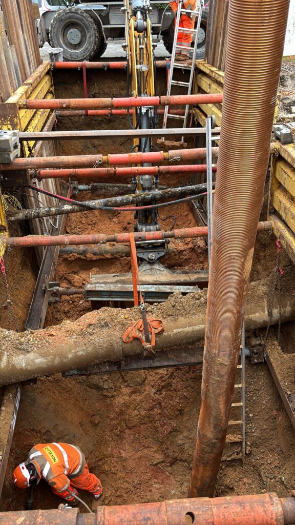 Ouvrier Novello dans une tranchée sécurisée par un blindage et des étais sur un chantier d'excavation.