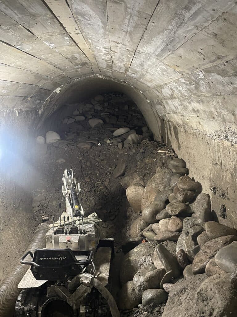 Robot excavateur Gerotto pour curage de tunnel Excavateur Gerotto télécommandé déblayant des roches dans un tunnel voûté souterrain encombré.