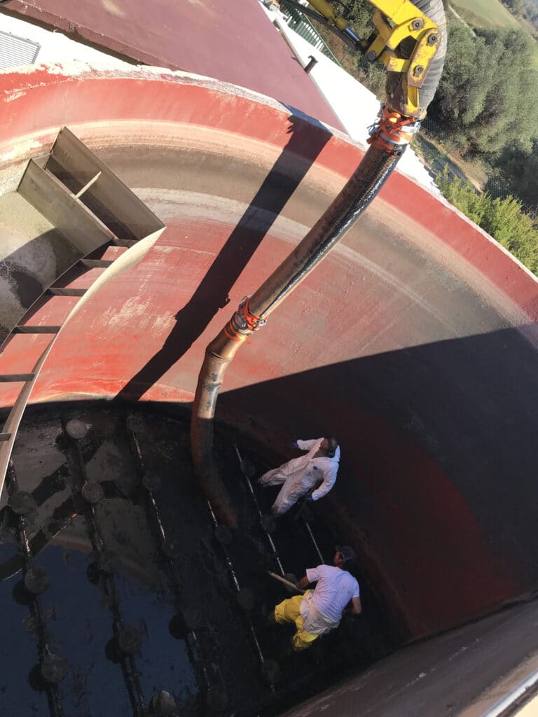 Nettoyage de Cuve Industrielle : Maintenance et Aspiration Nettoyage d'une cuve industrielle par aspiration avec deux techniciens en tenue de protection.