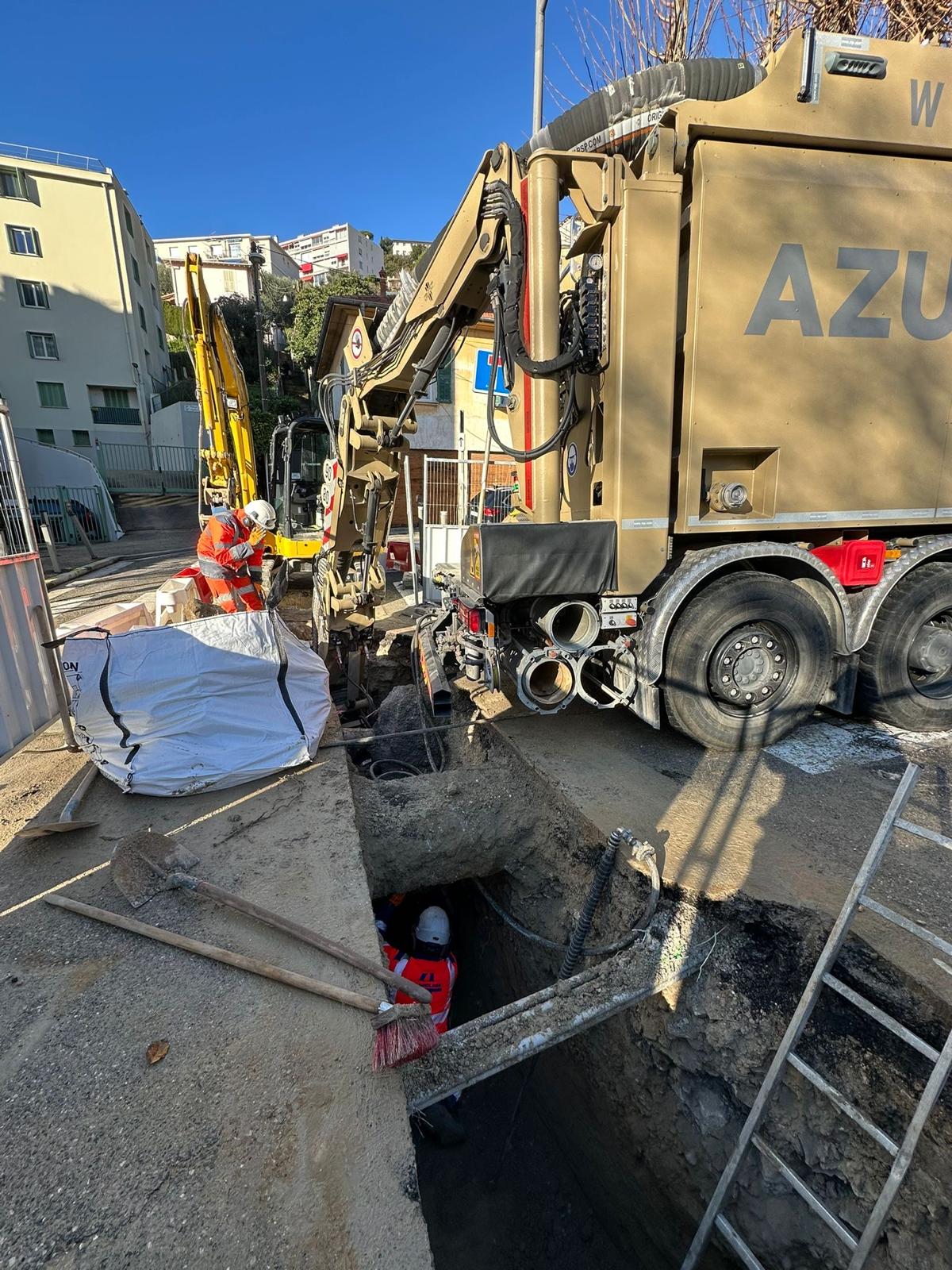 Ouvriers dans une tranchée sur un chantier avec une aspiratrice excavatrice AZUR et matériel de terrassement.