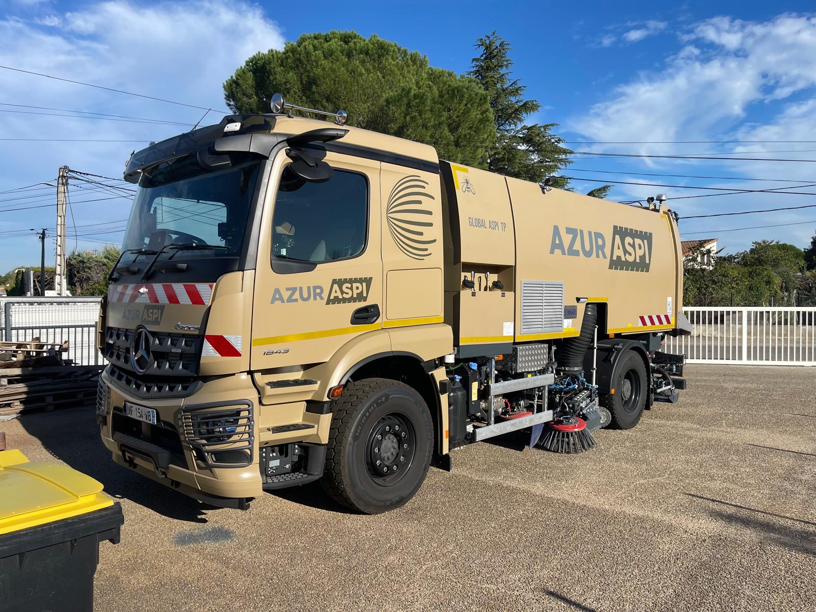 Camion balayeuse Mercedes Arocs 1843 beige Azur Aspi avec brosses de nettoyage sur un parking ensoleillé.