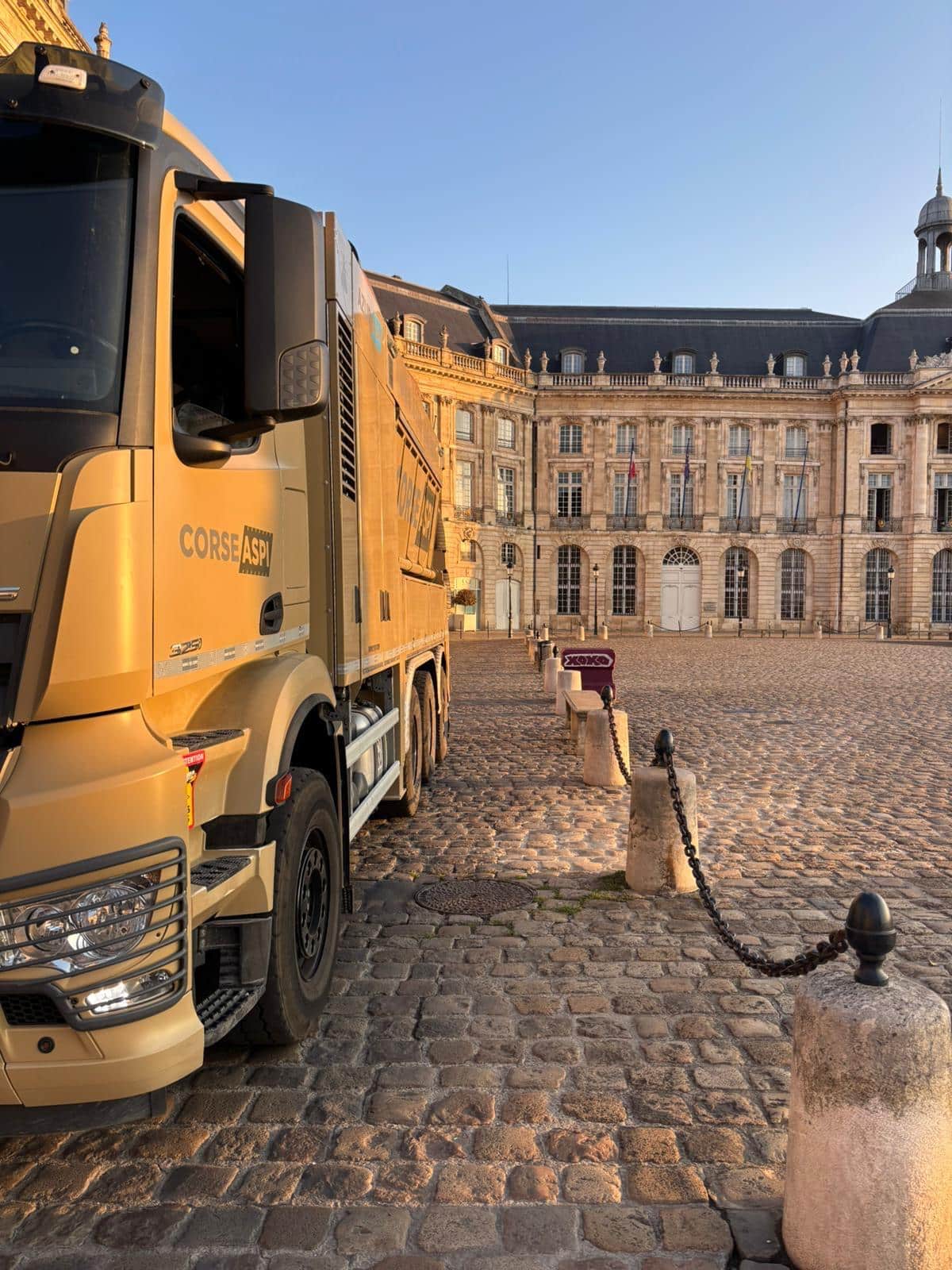 Camion Corse Aspi doré stationné sur les pavés de la Place de la Bourse à Bordeaux.