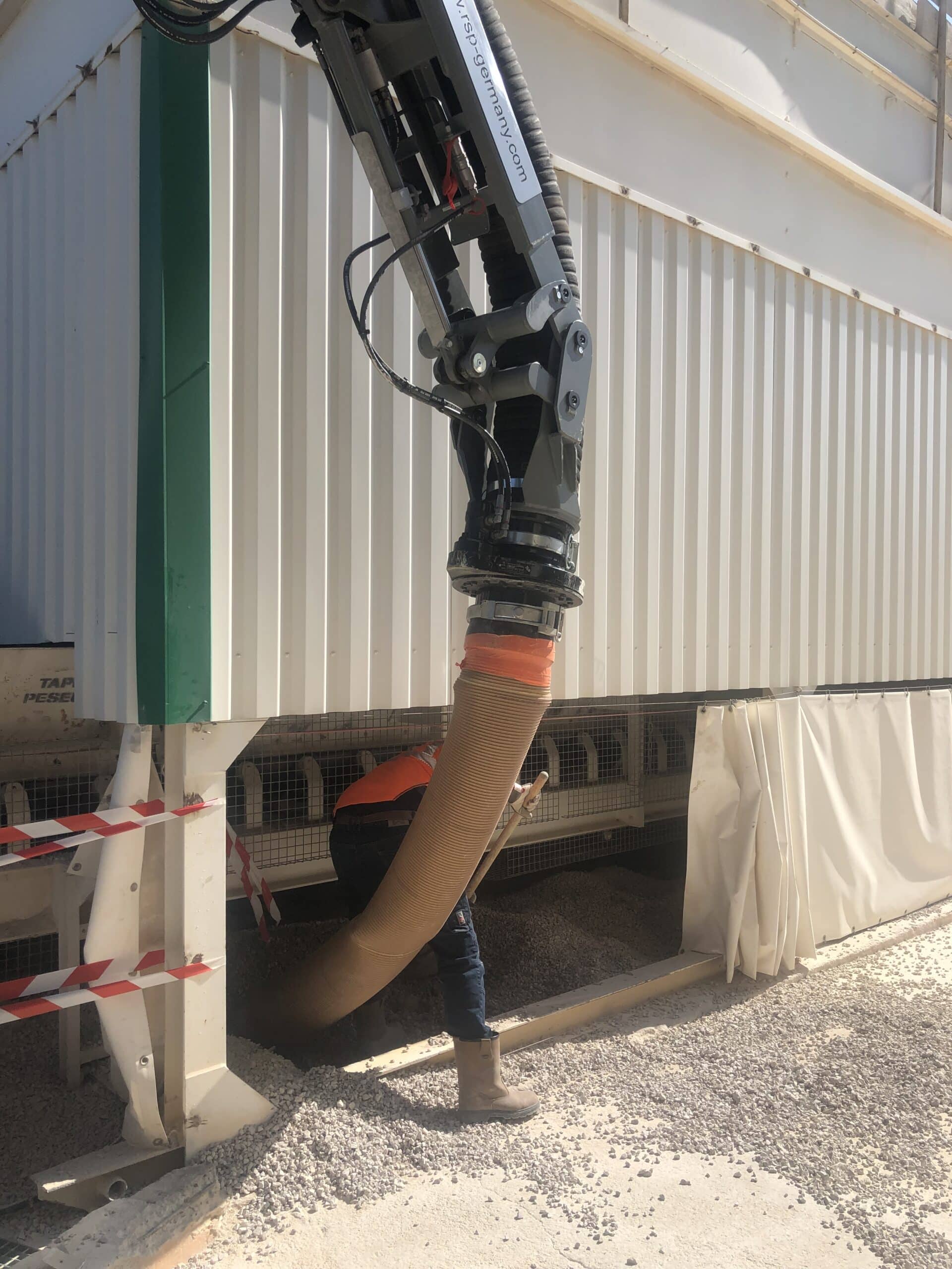 Ouvrier manipulant un tuyau d'excavation par aspiration RSP pour retirer du gravier sur un chantier industriel.