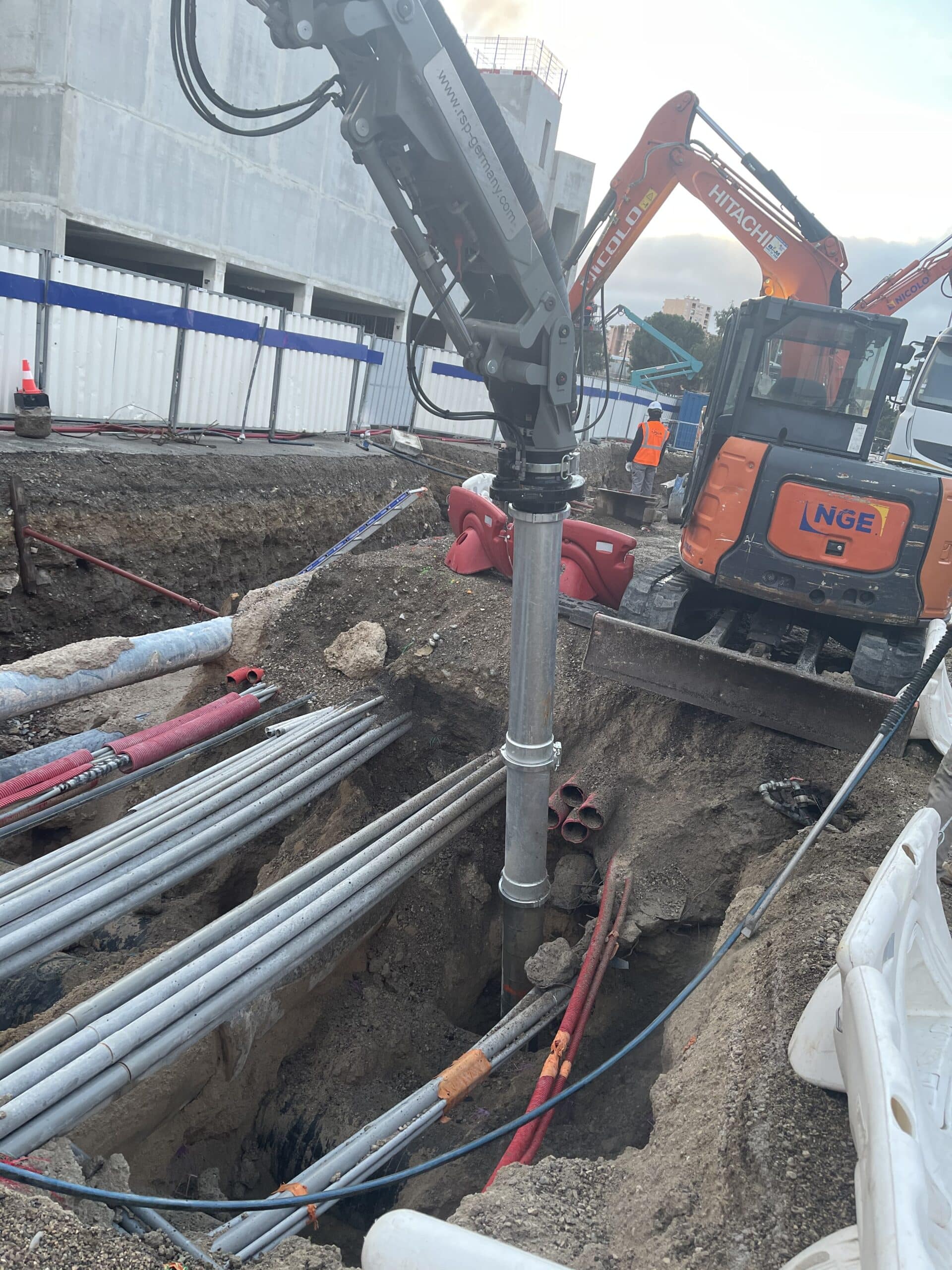 Excavatrice aspiratrice RSP et mini-pelle Hitachi NGE sur un chantier avec de nombreuses canalisations en tranchée.