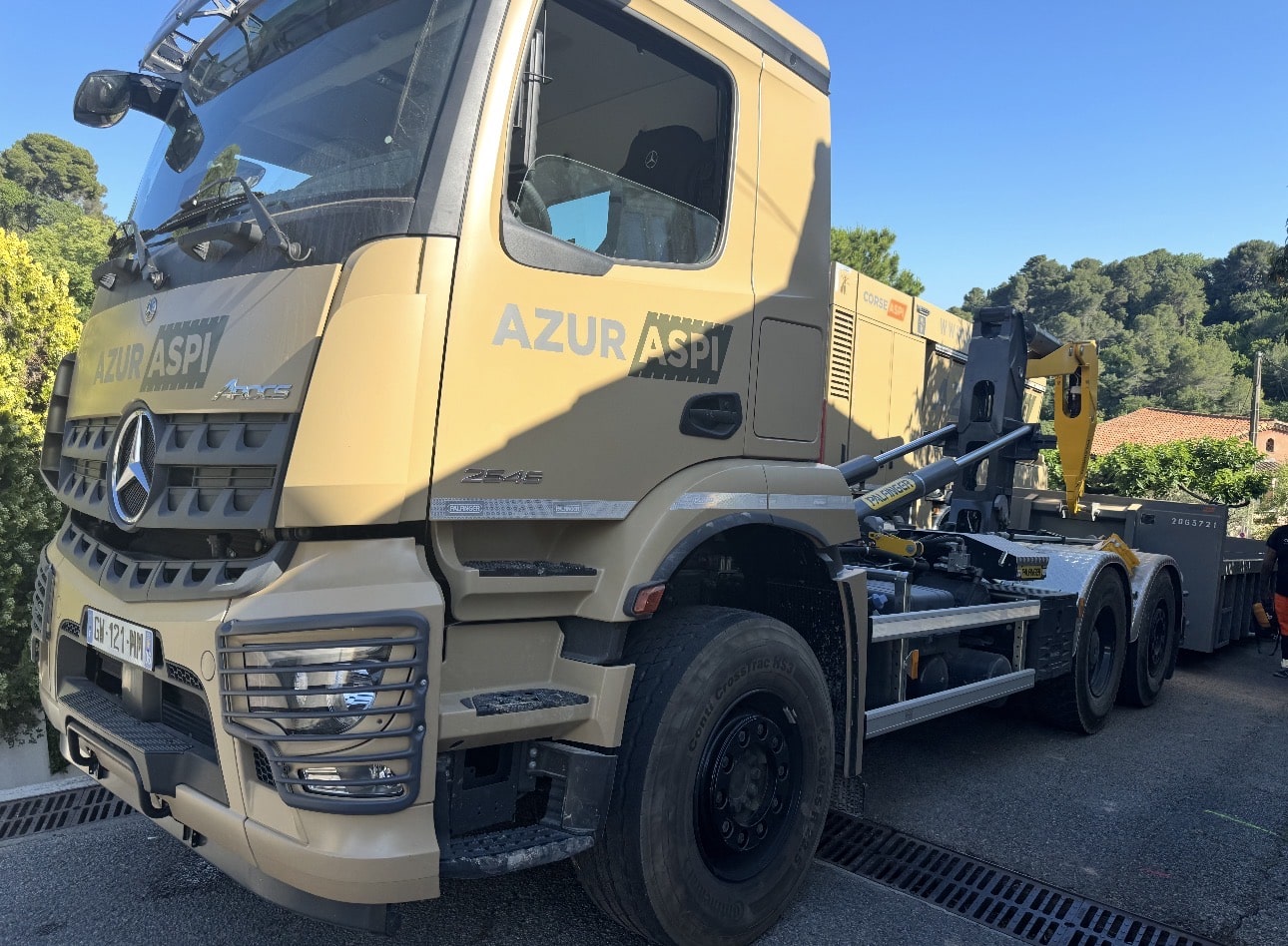 Camion Mercedes Arocs beige Azur Aspi avec bras articulé Palfinger stationné dans une rue ensoleillée.