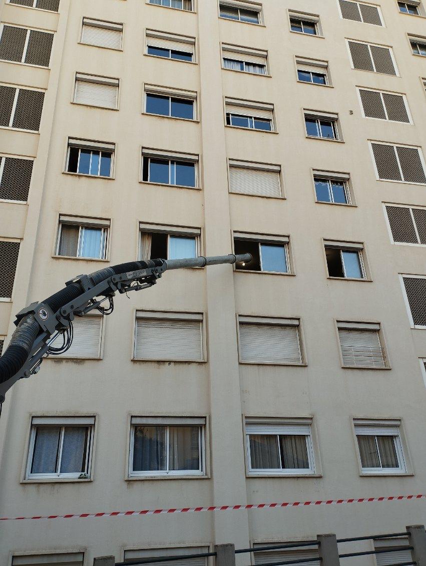 Bras articulé d'une pompe inséré dans la fenêtre d'un grand immeuble pour des travaux de rénovation ou isolation.